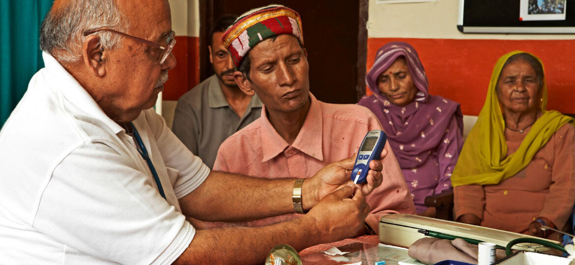 Doctor using instrument checking blood sugar level of diabetes patient in health centre started by NGO Chinmaya Organization